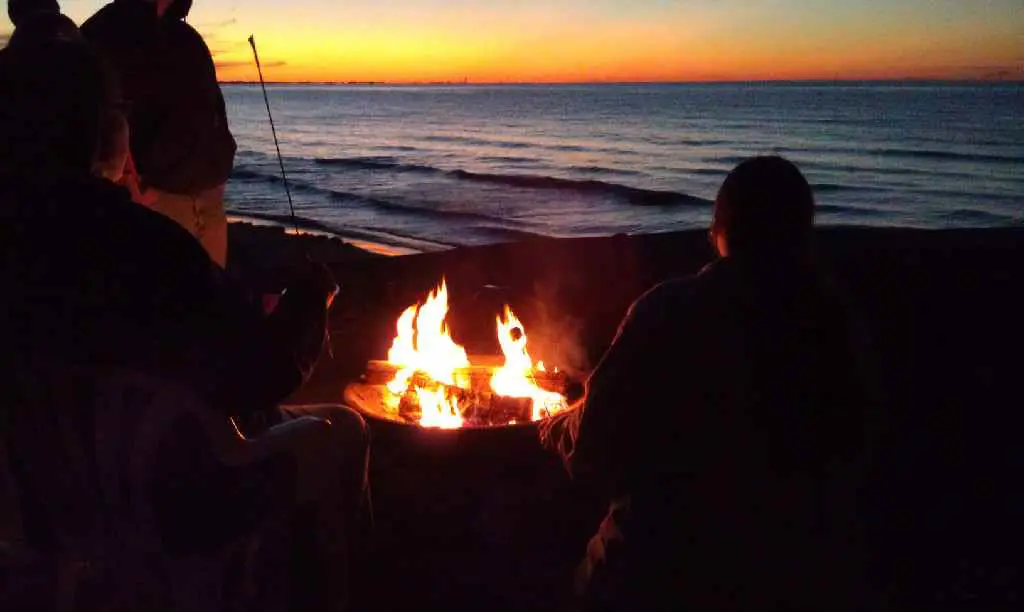 People sitting near the beach with campfire